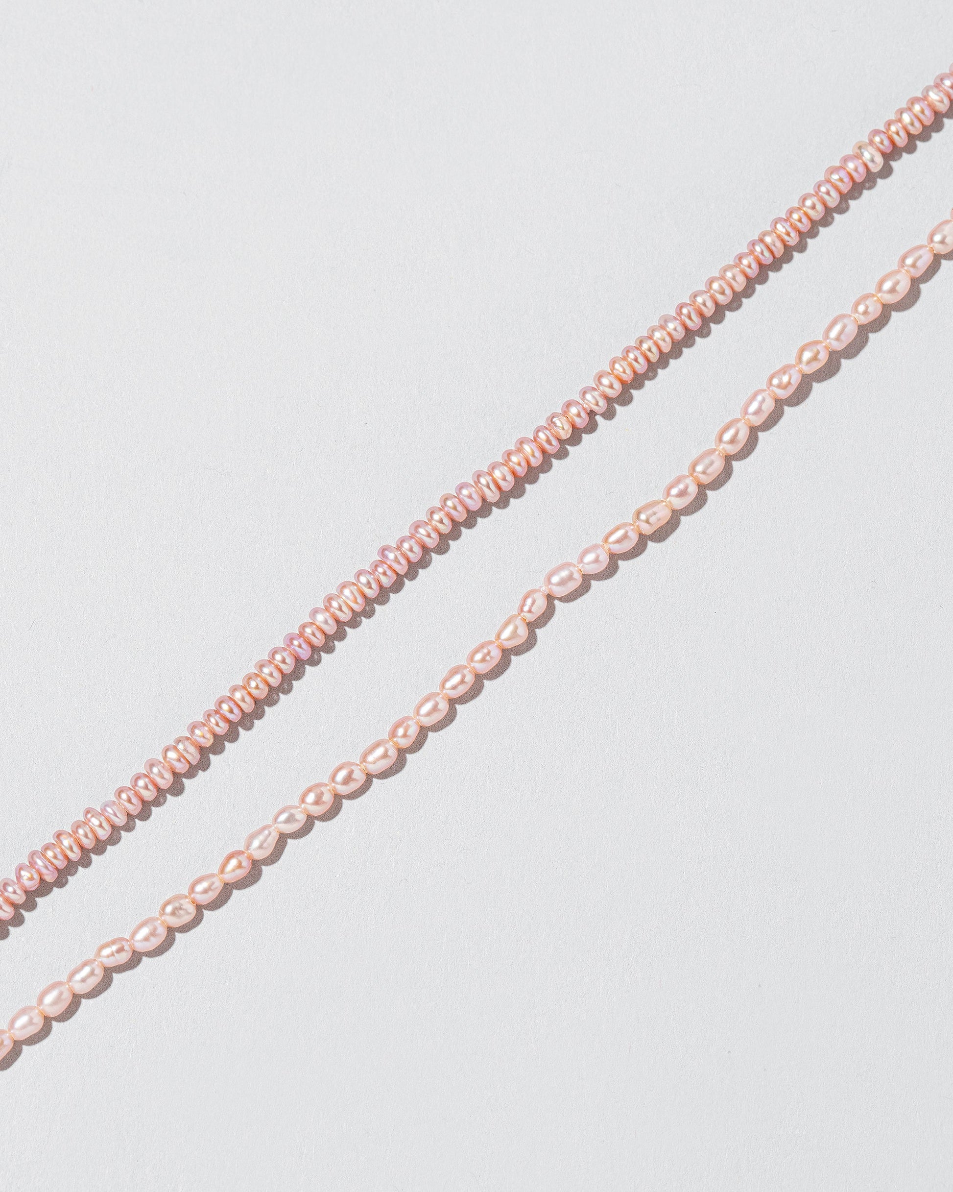 Closeup details of the Pink Peony Pebble Seed Pearl Choker Necklace & Pink Peony Oval Seed Pearl Choker Necklace on light color background.