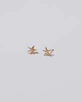 Closeup details of Shape Two Small Verve Six Point Star Stud Earrings on light color background.