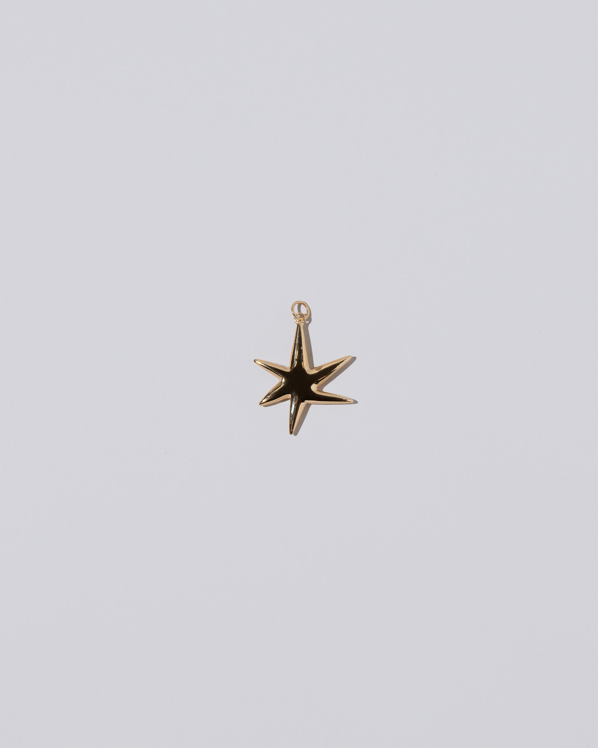 Gold Large Verve Six Point Star Charm on light color background.