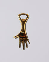 Carl Auböck Brass Hand Bottle Opener on light color background.