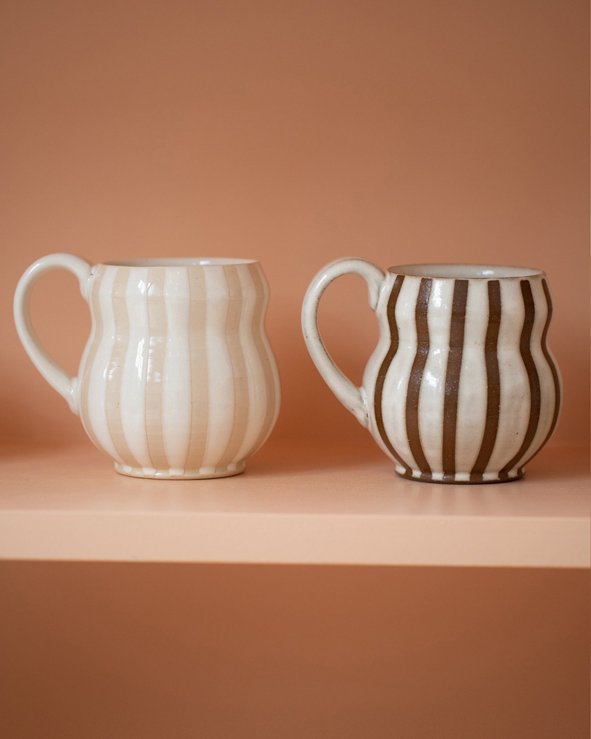 Styled image of the Jeremy Ayers Mugs Set of Two, including the White and Brown  Bubble Mugs, on shelf.