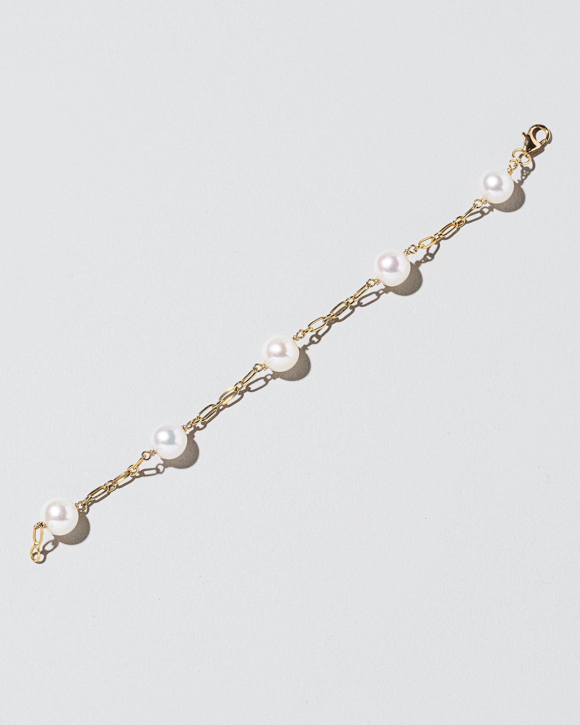 Five Pearl Station Bracelet Hot Dog Chain on light color background.