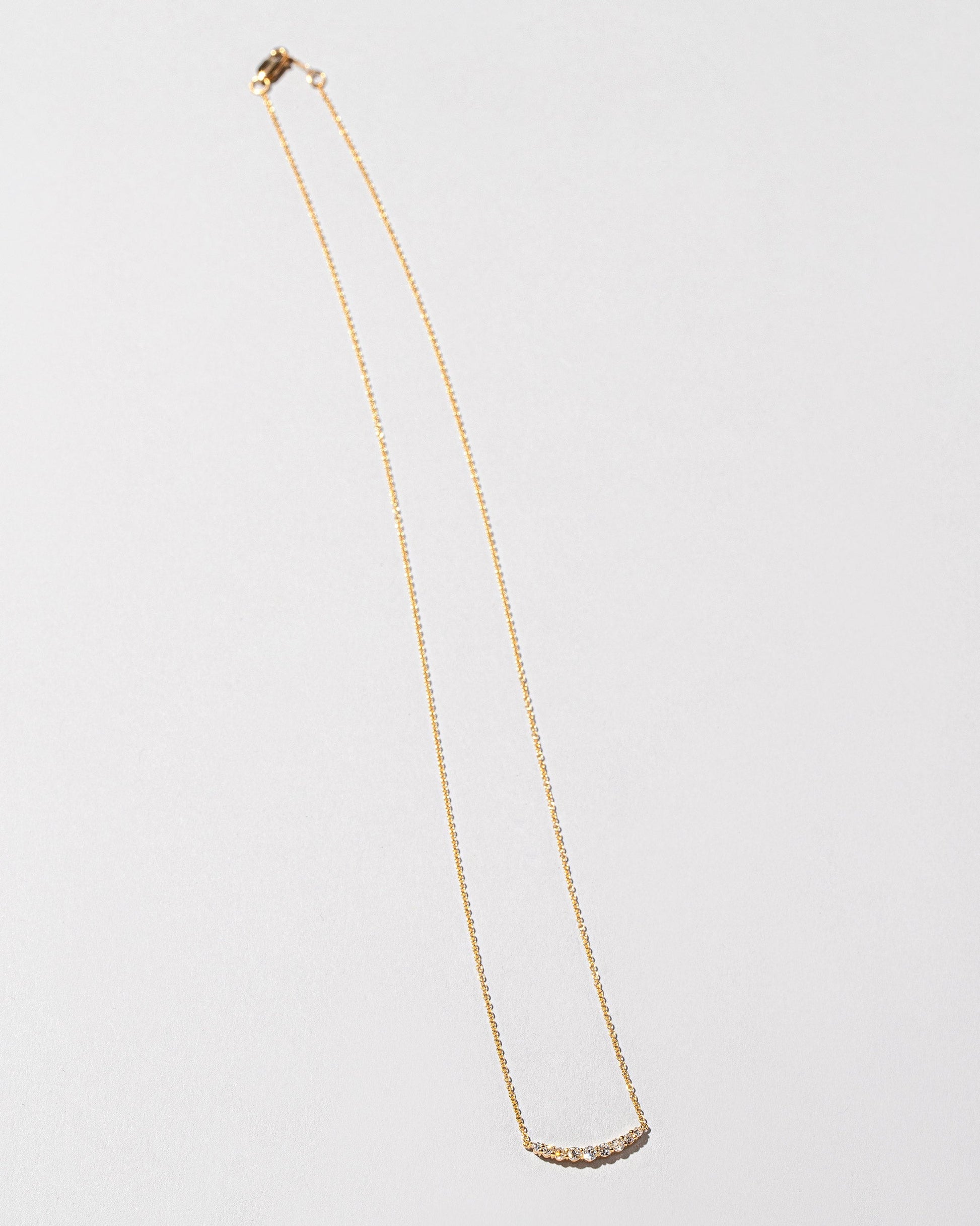 White Diamond Crescent Necklace on light color background.