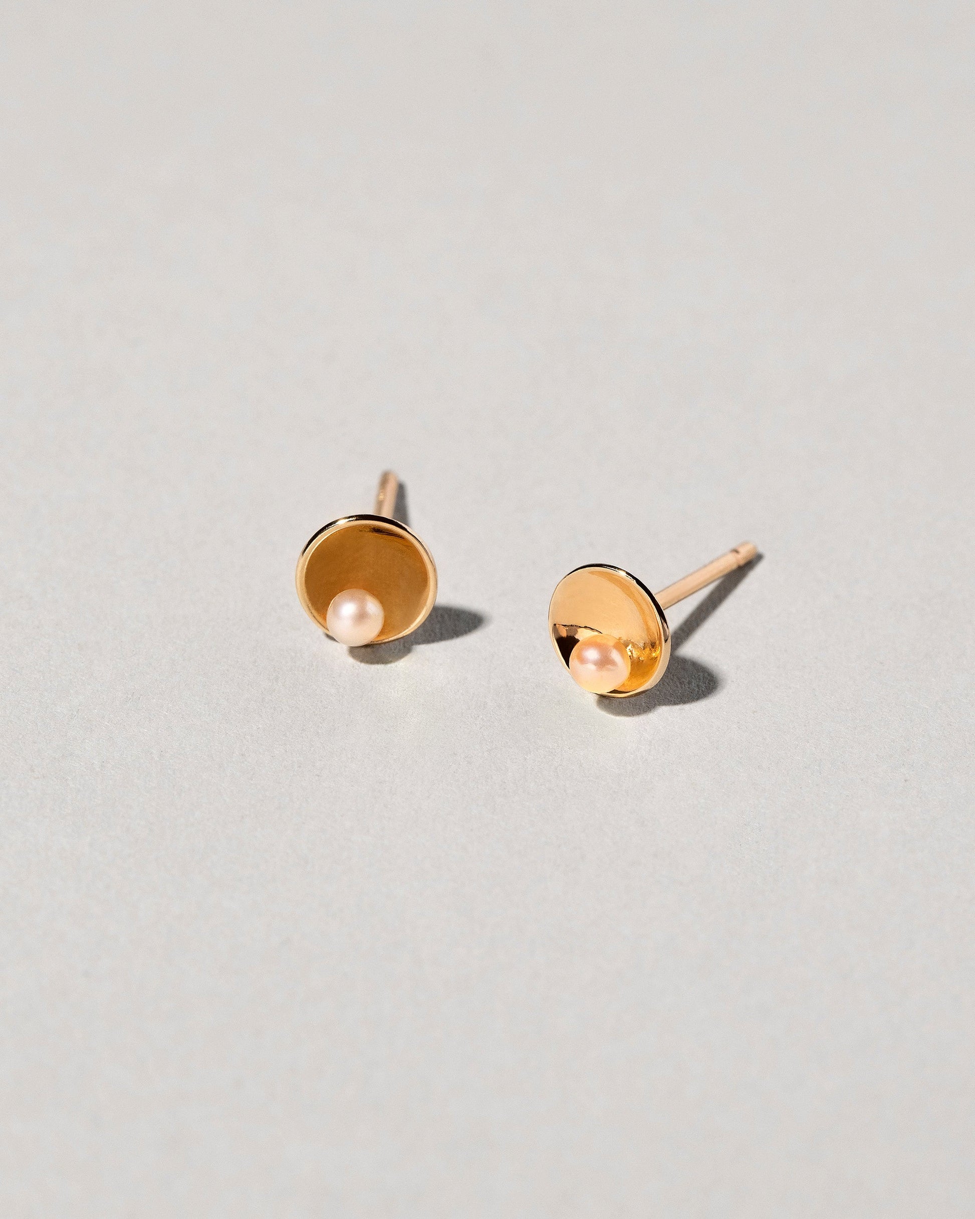 Pearl Cup Earrings on light color background.