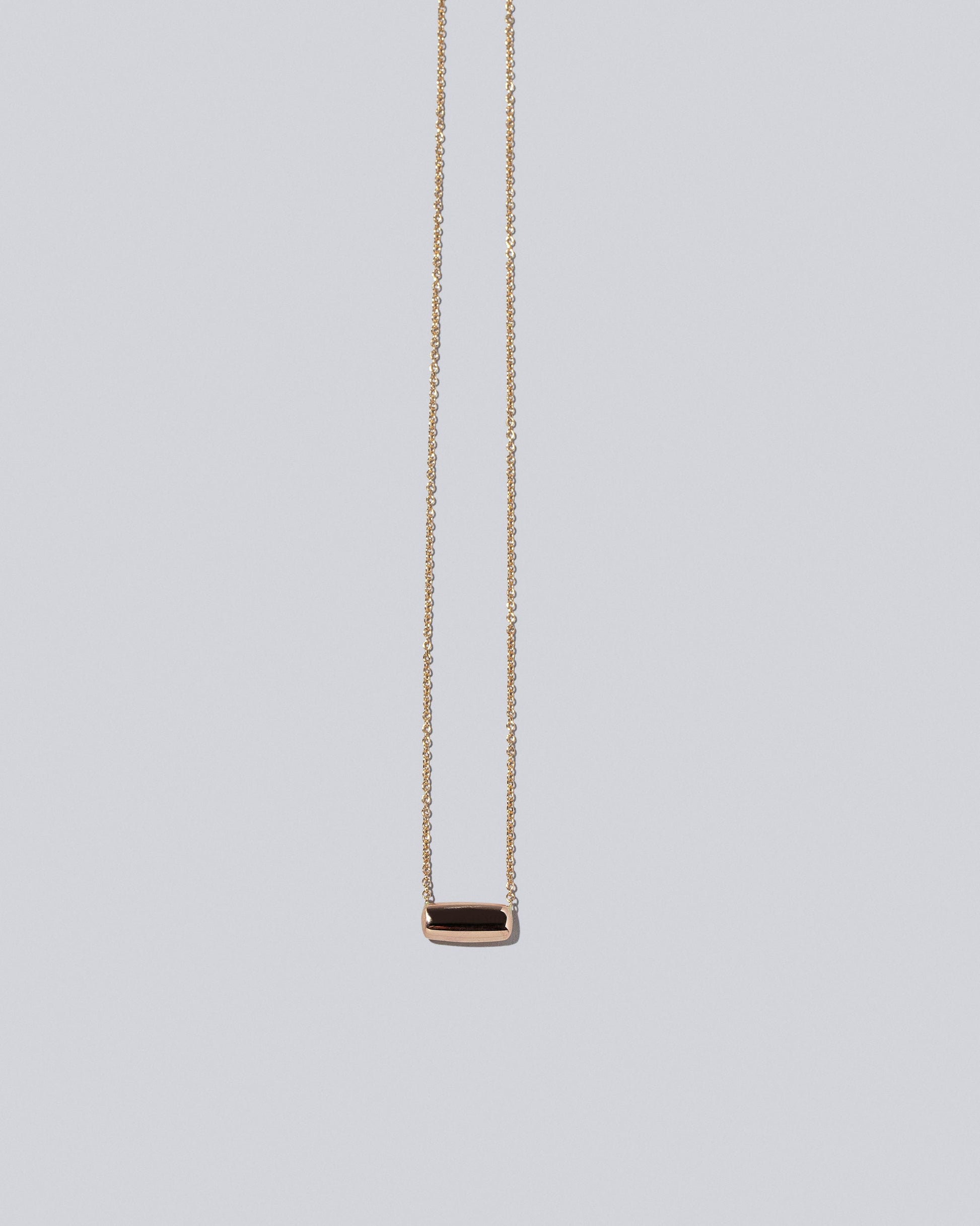 Closeup detail of Rectangle Time Capsule Necklace on light color background.