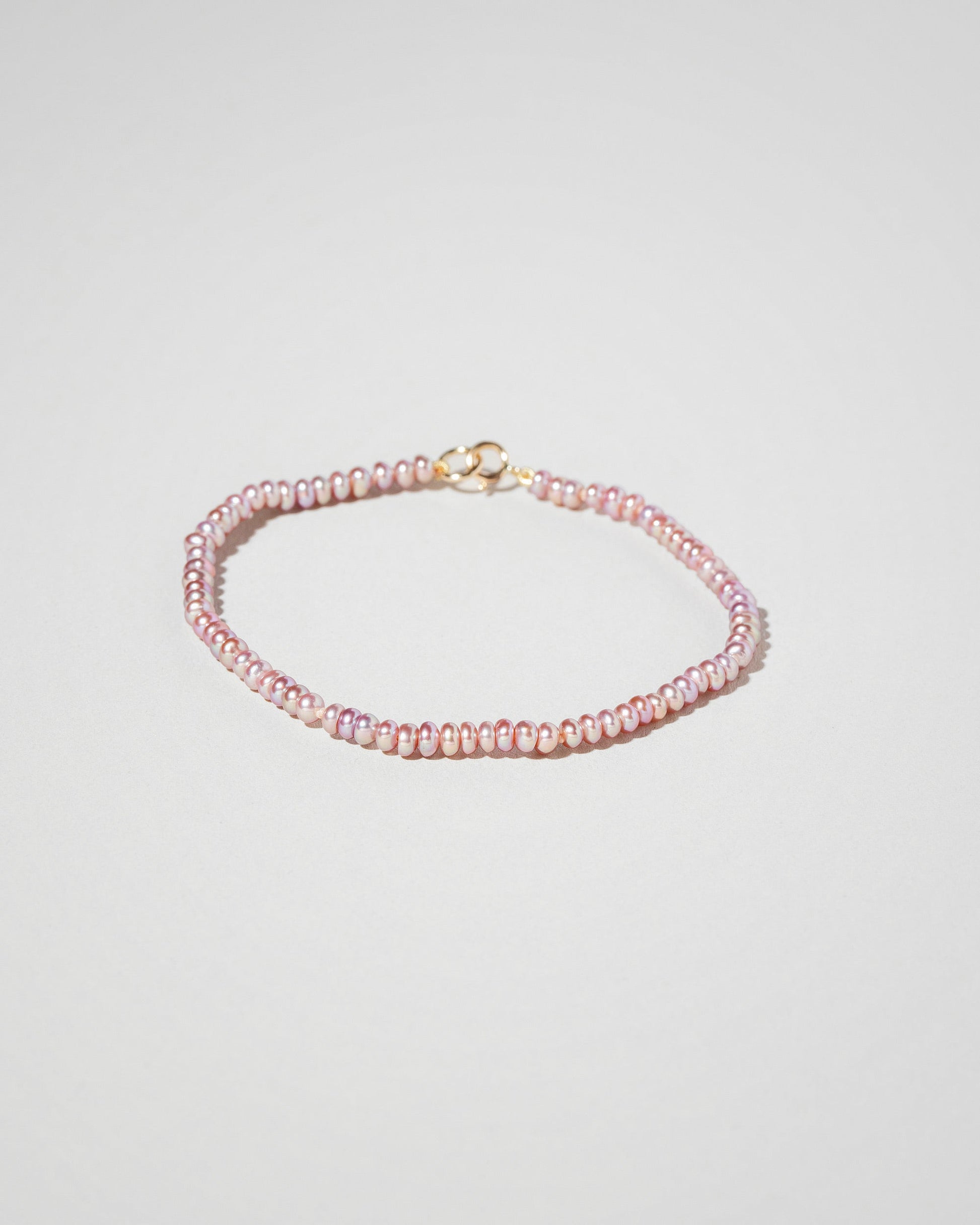 Closeup details of the Pink Lavender Seed Pearl Bracelet on light color background.