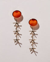 Red Sun Earrings on light color background.
