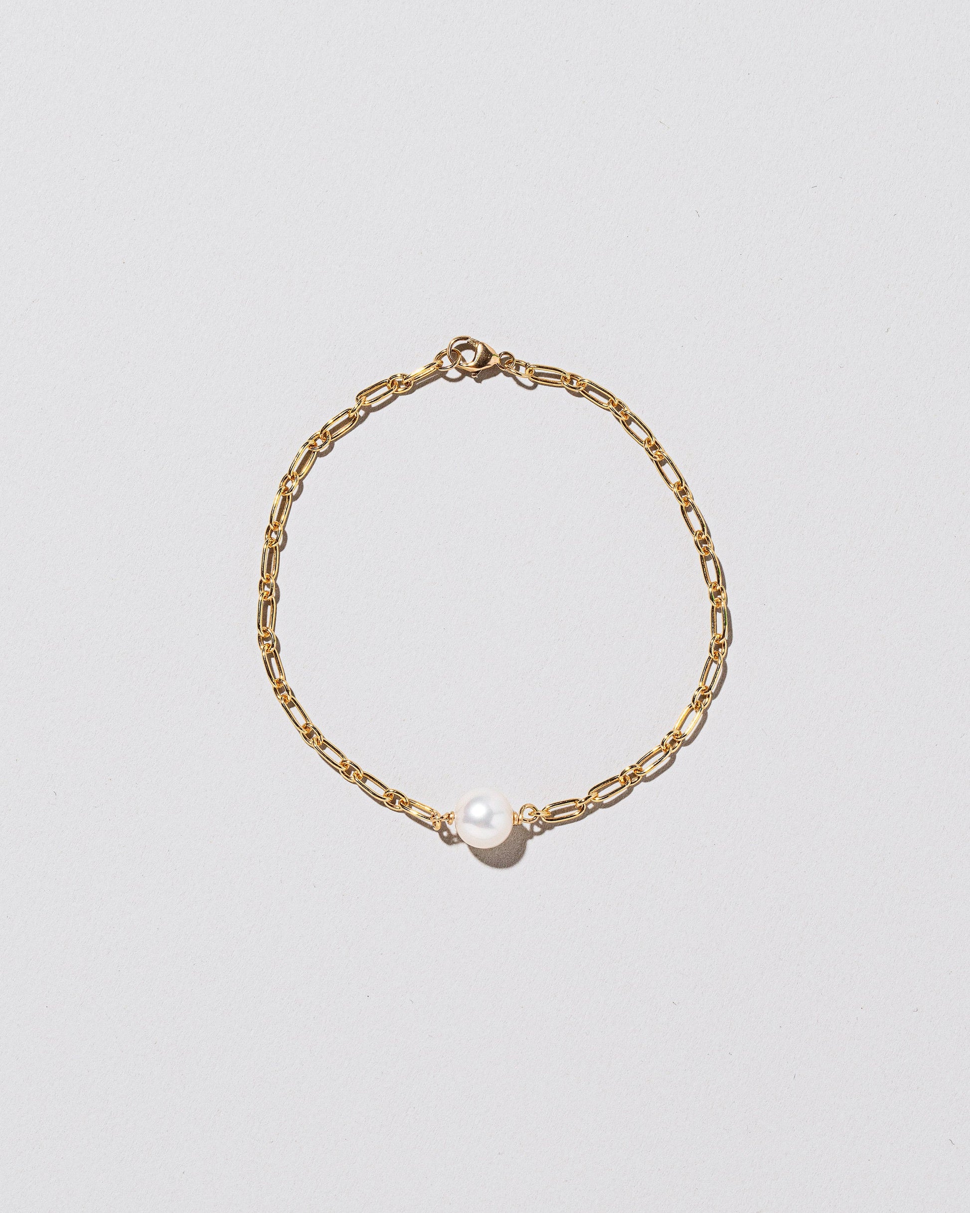 One Pearl Station Bracelet Hot Dog Chain on light color background.