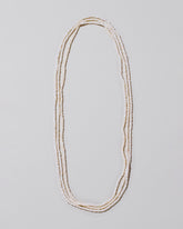 White Seed Pearl Rope Necklace on light color background.