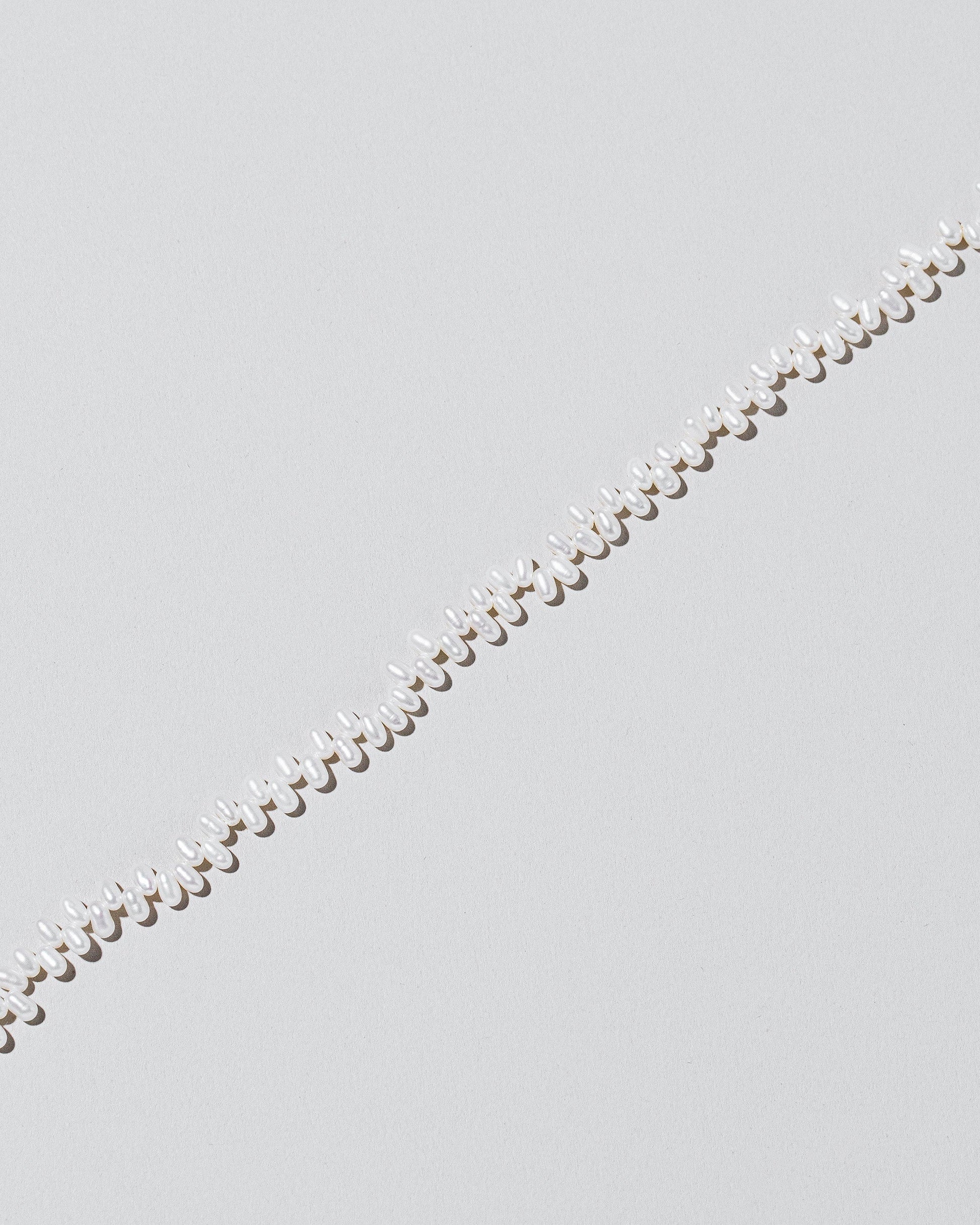 Closeup details of the Small Zipper Pearl Necklace on light color background.