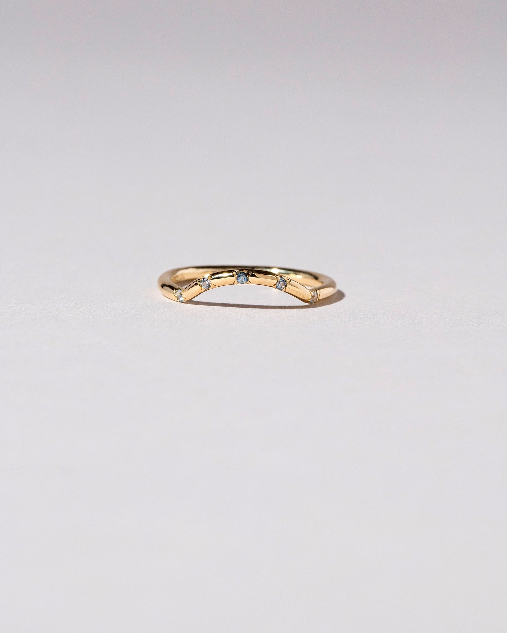 Gold Five Stone Blue Sapphire Mini Curve Band on light color background.