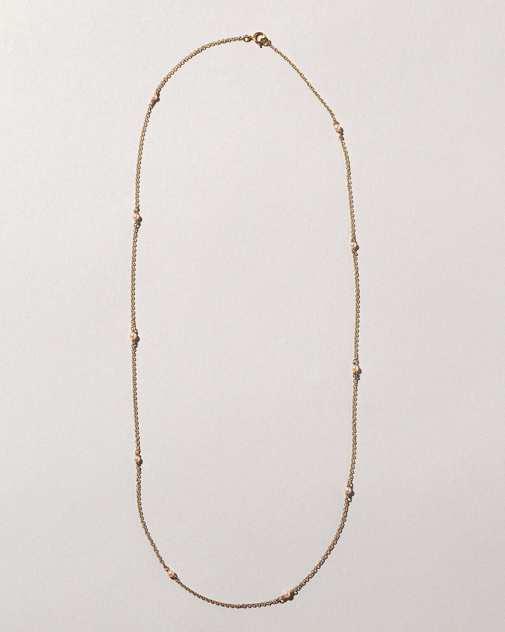 Natural Pink Seed Pearl Necklace on light color background.
