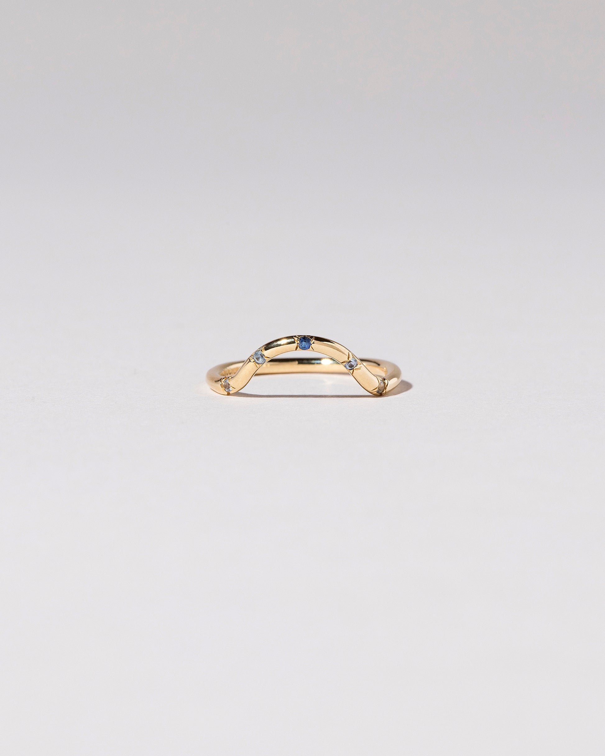 Gold Blue Sapphire Five Stone Curve Band on light color background.
