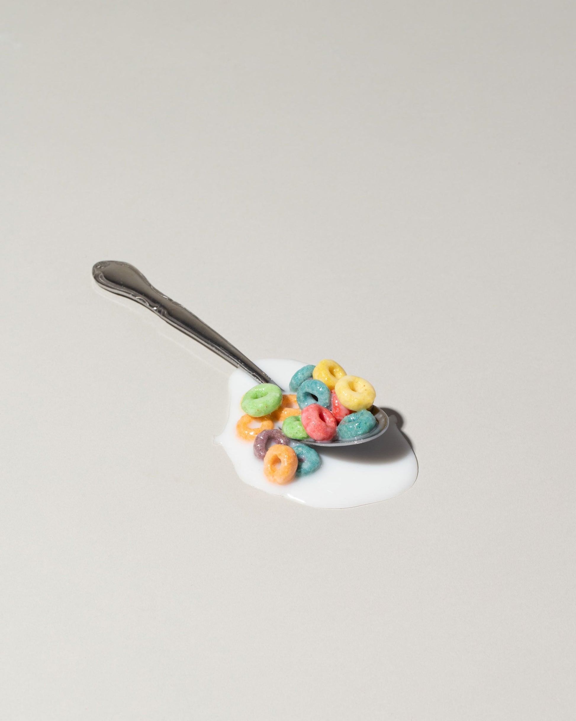 Spills Fruit Loops Spoon on light color background.