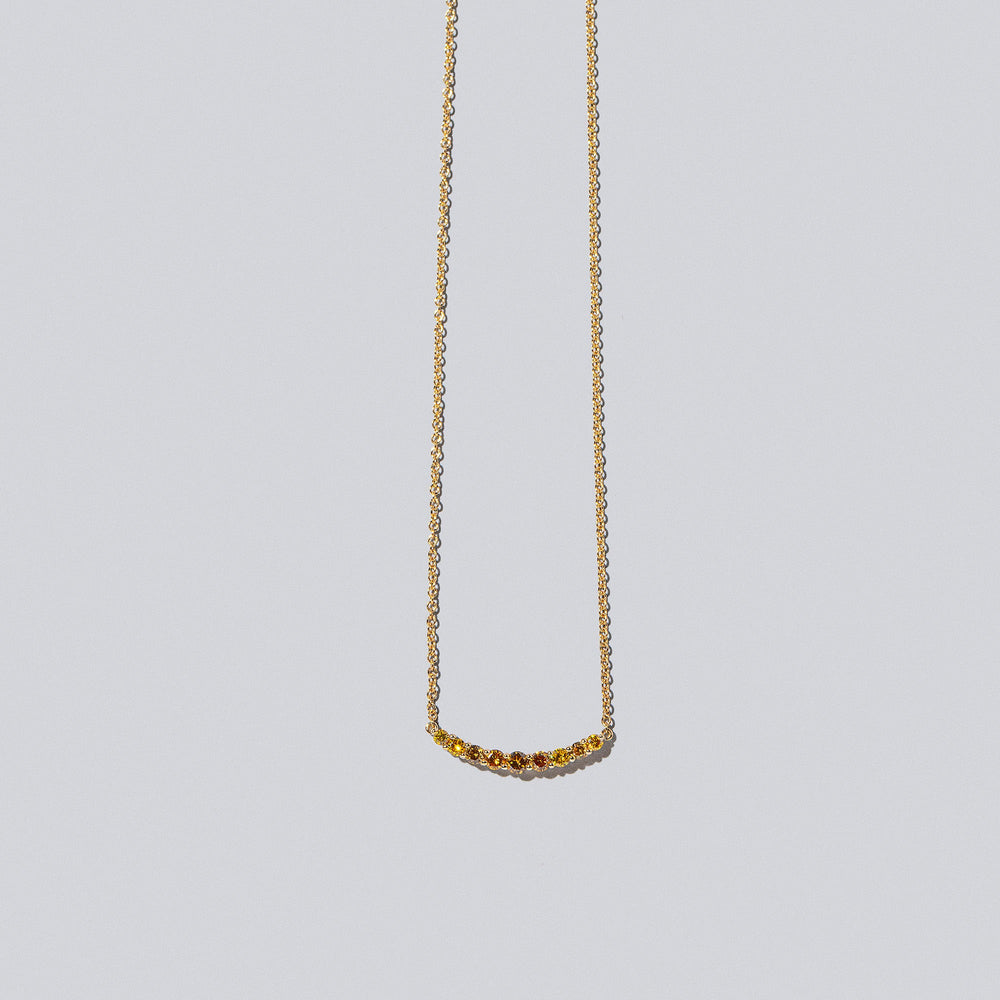product_details::Closeup detail of the Yellow Diamond Crescent Necklace on light color background.