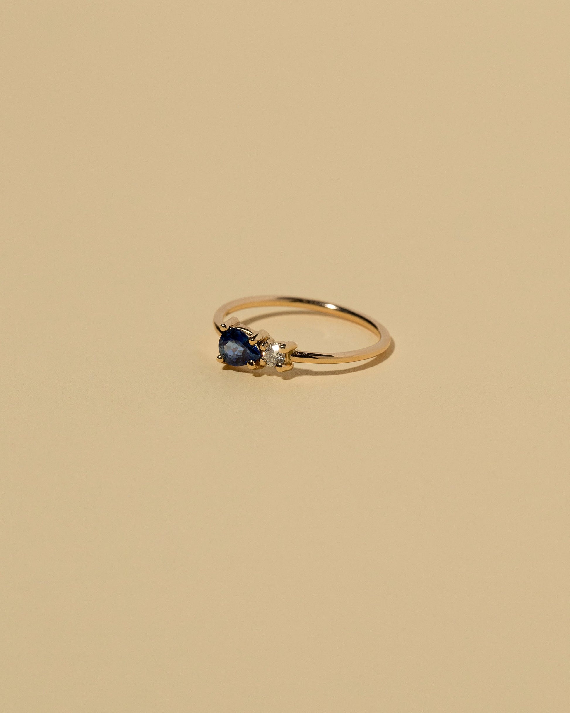 View from the side of the Blue Sapphire Teardrop Ring on light color background.