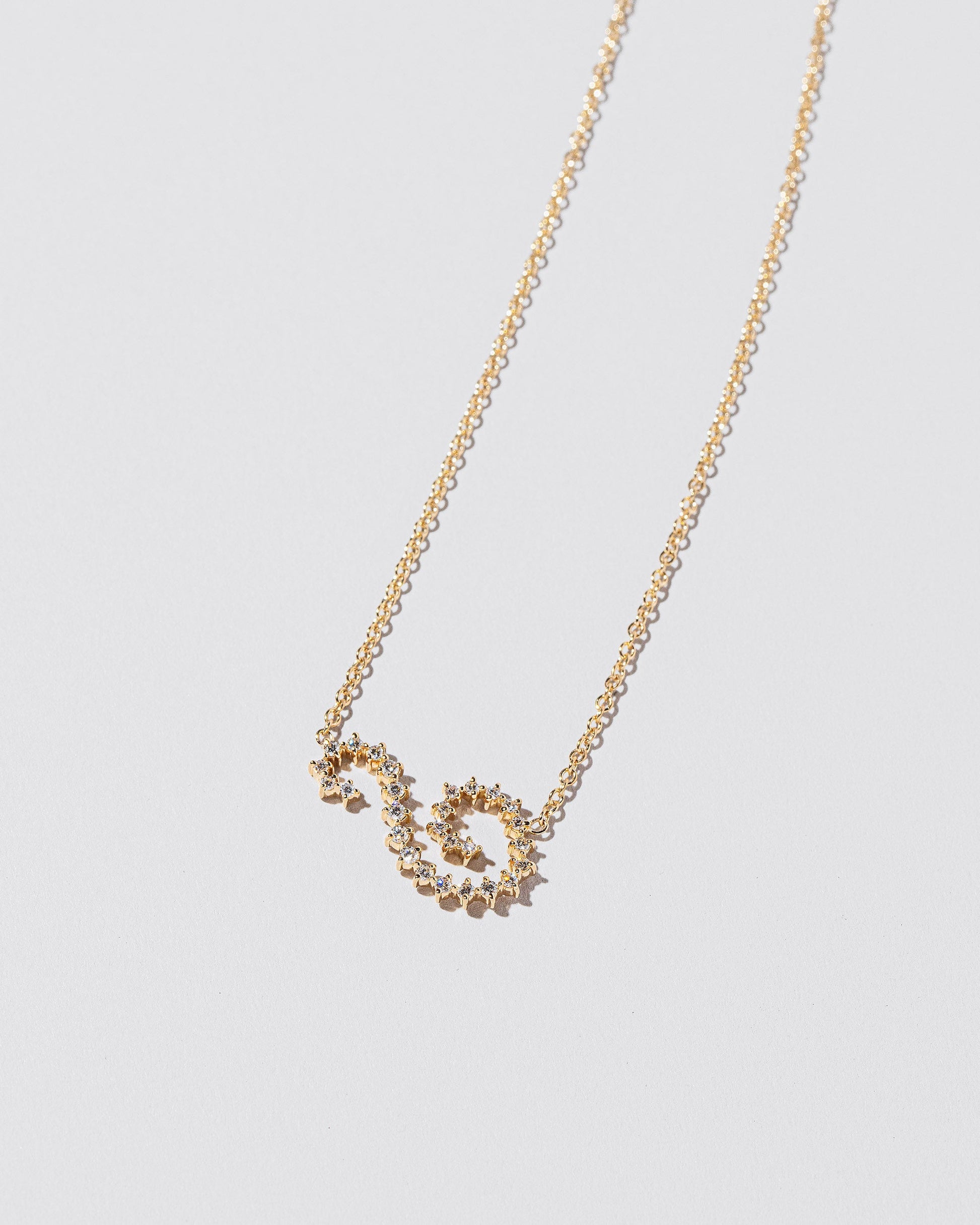 Closeup details of the White Diamond Symbol of Change Necklace on light color background.