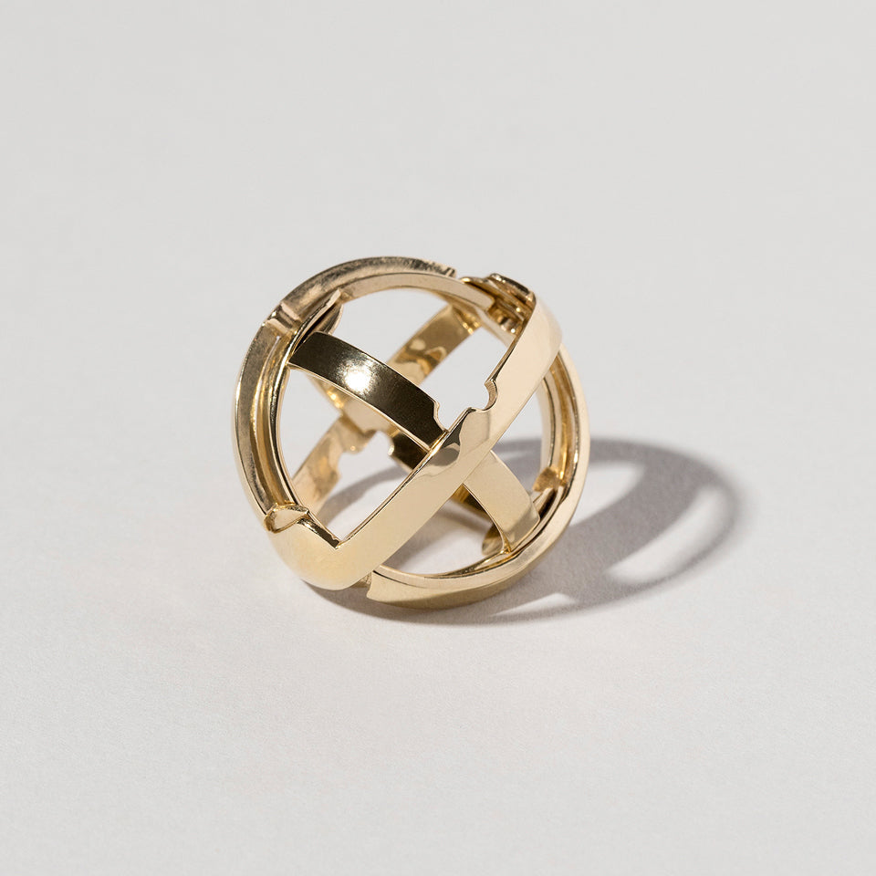 product_details::Closeup details of the Armillary Sphere Band on light color background.