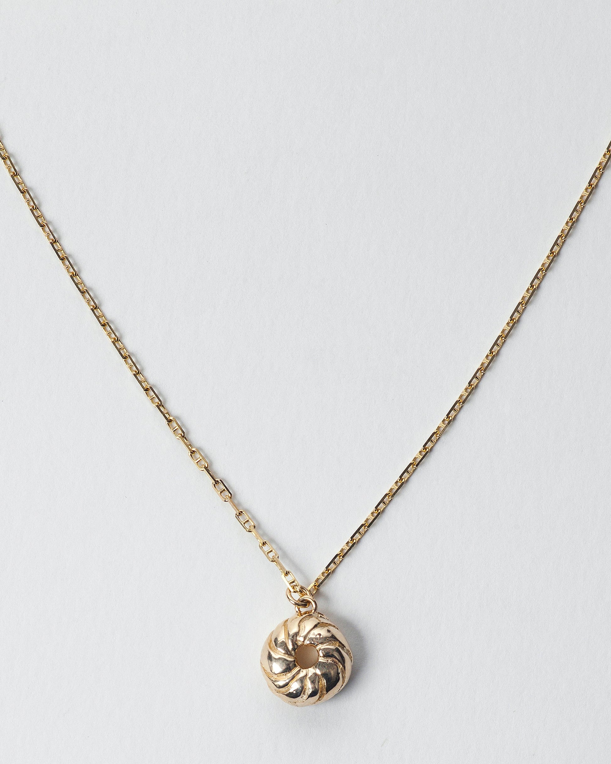 French Cruller Charm on chain, on light color background.