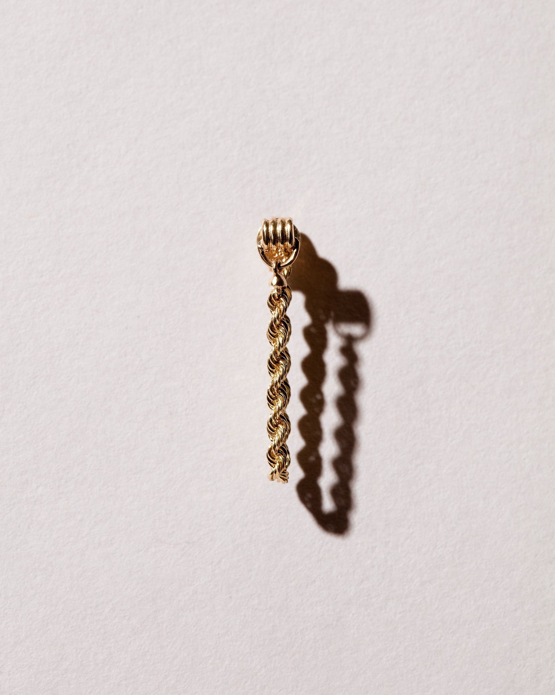 Closeup details of the Golden Twist Stud Earring Single on light color background.