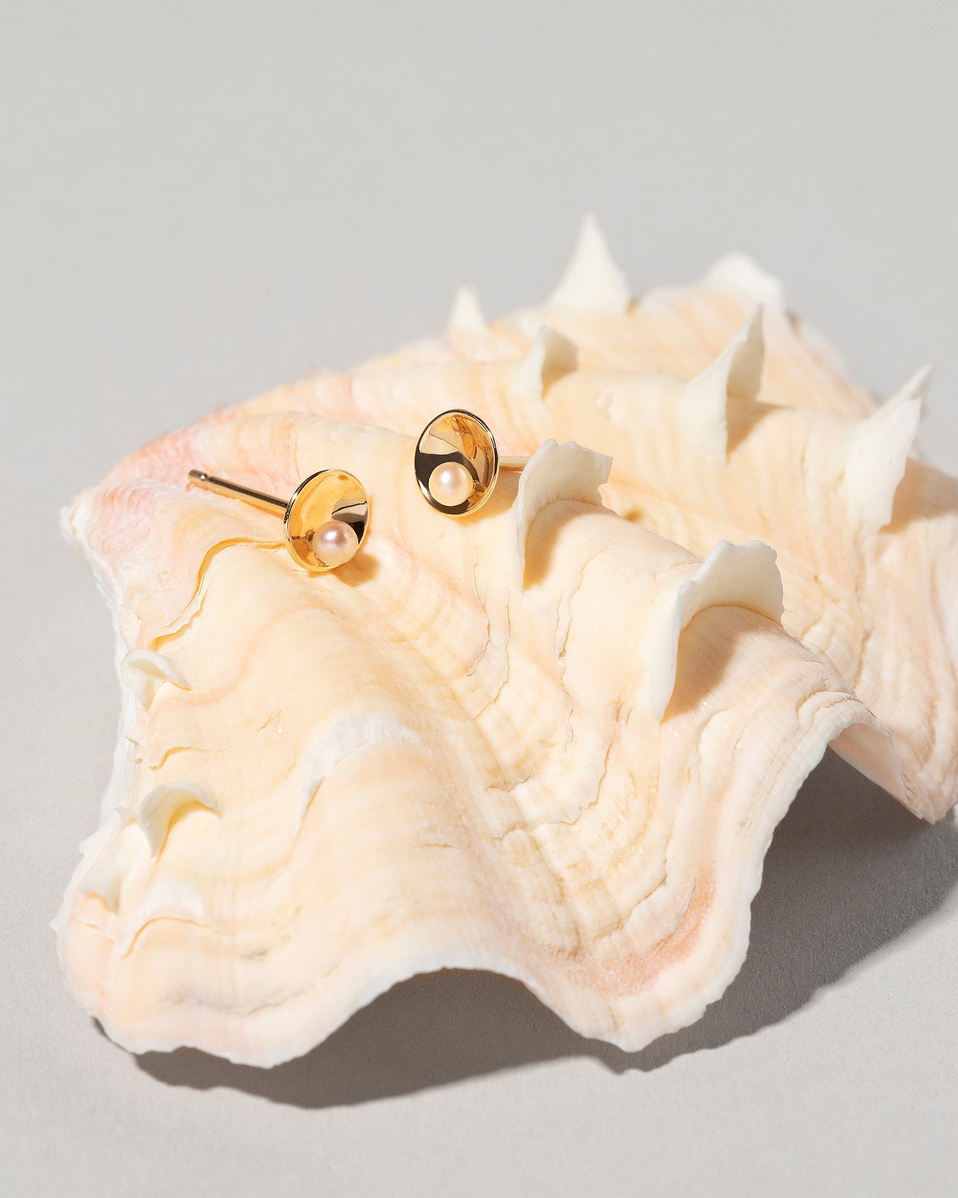 Pearl Cup Earrings on light color background.