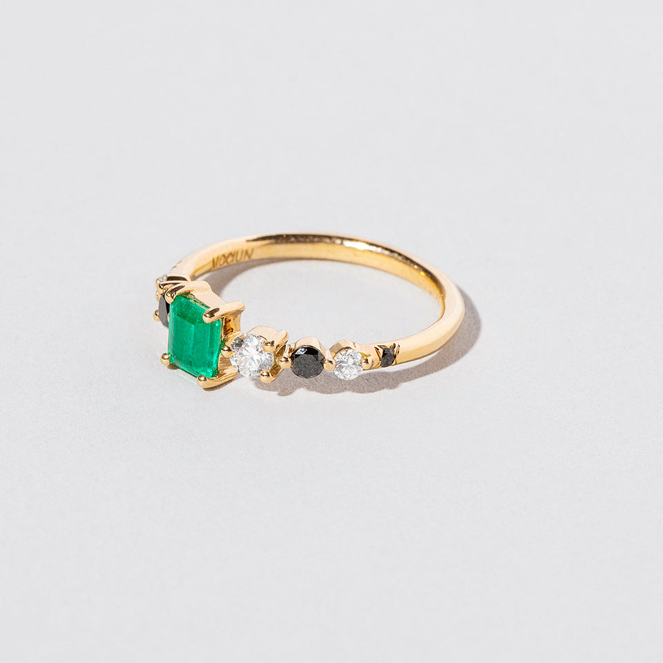 product_details::Closeup details of the Emerald Seven Sisters Ring on light color background.