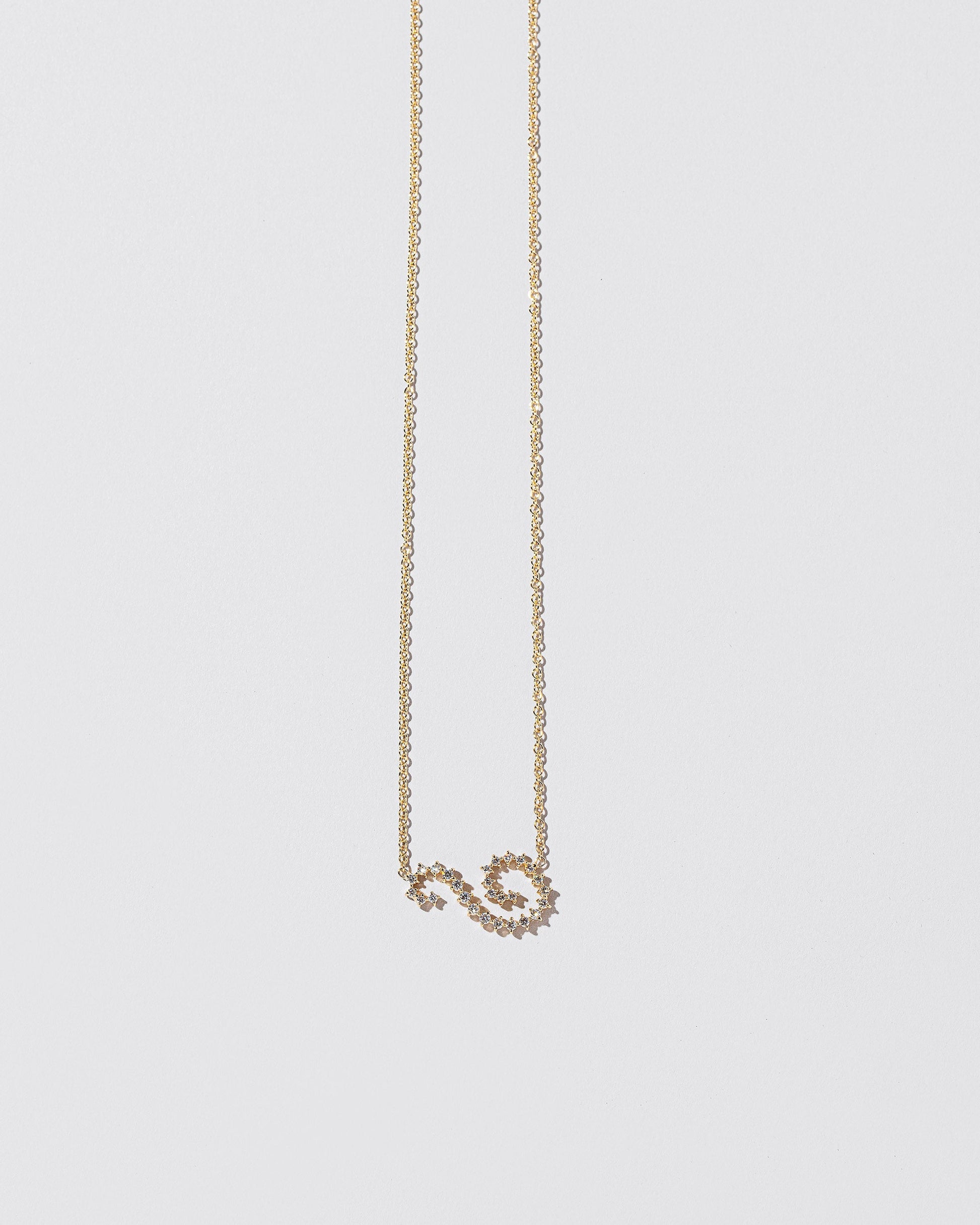 White Diamond Symbol of Change Necklace on light color background.