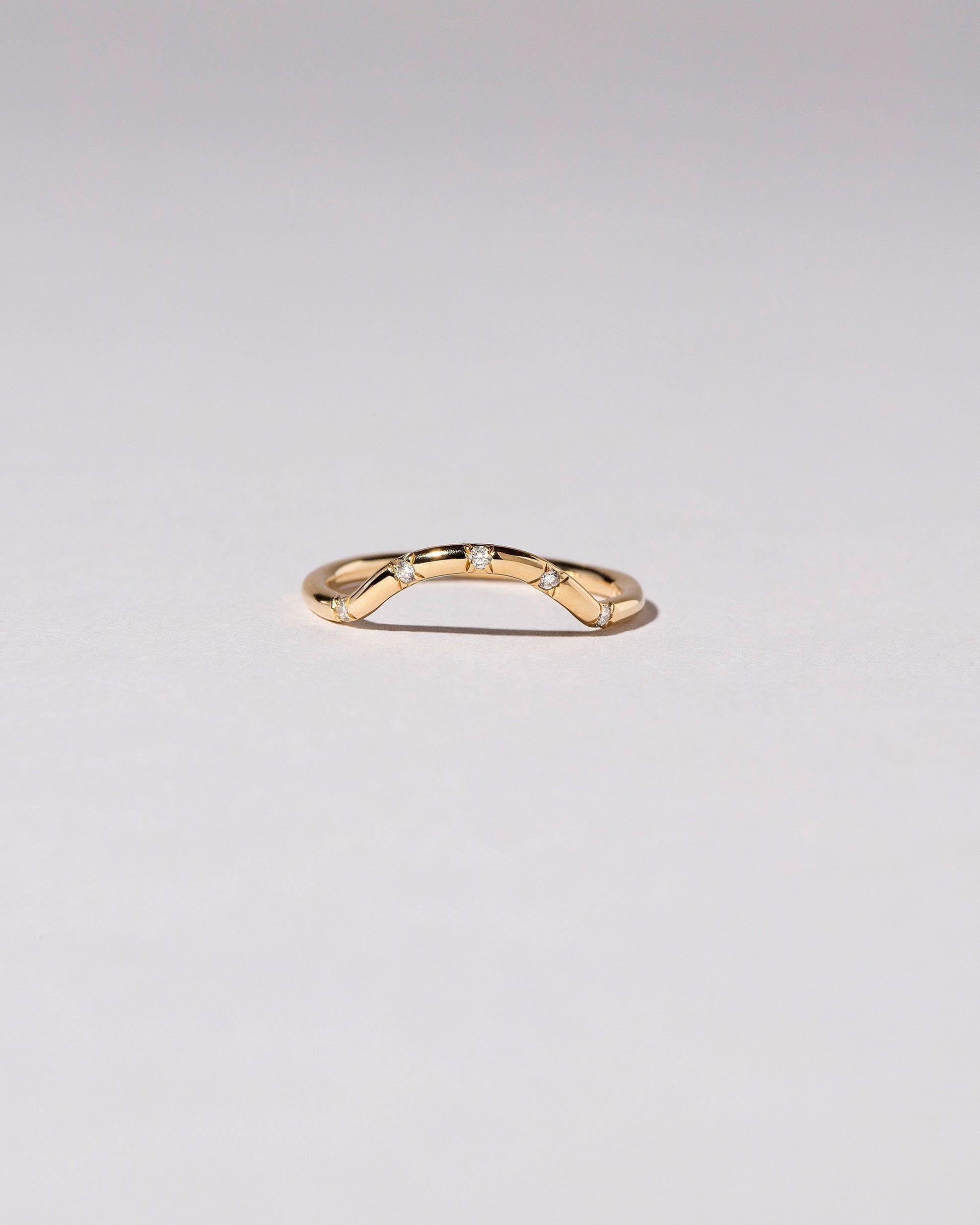 Gold Five Stone White Diamond Mini Curve Band on light color background.