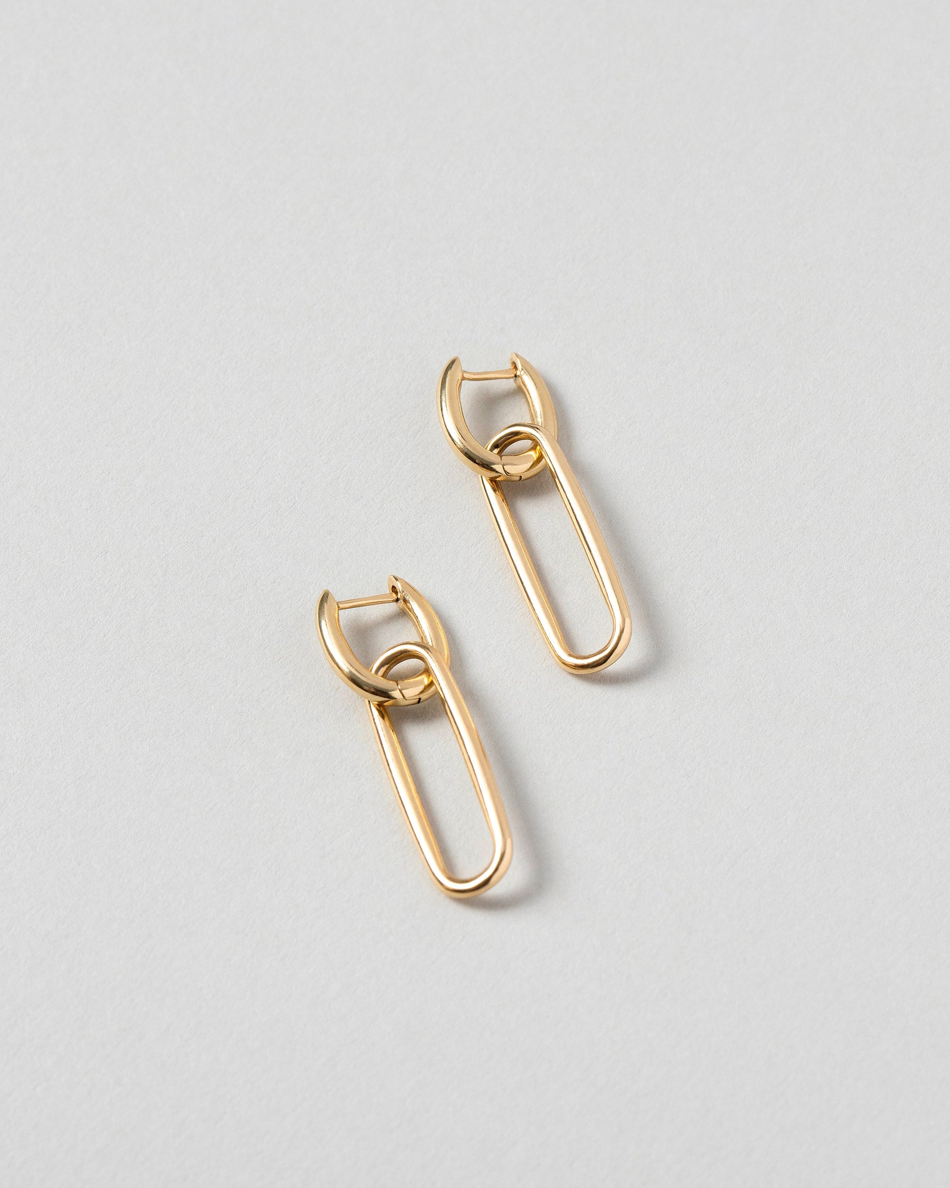 Solid Link Huggie Hoop Earrings on light color background.