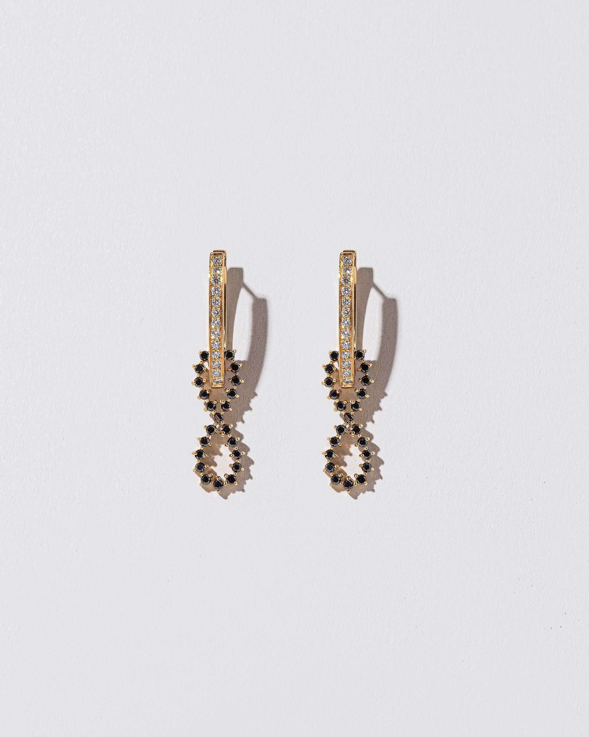 White Diamond and Black Diamond Lifecycle Earrings on light color background.