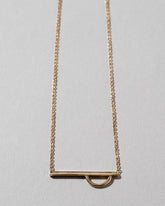 Tilt Dance Necklace on light color background.