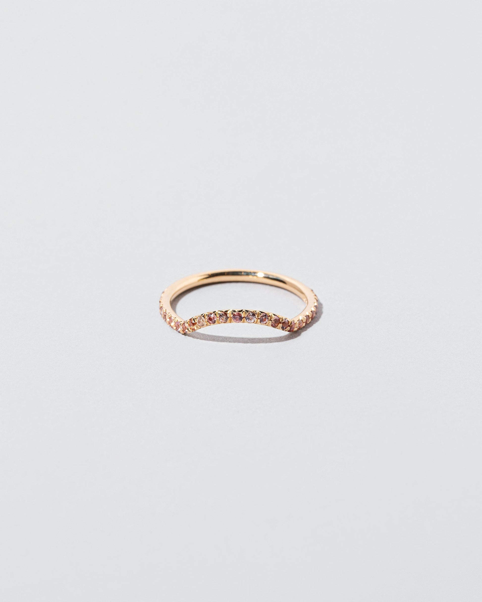 Mini Curve Band with pavé set peach sapphires on light color background.