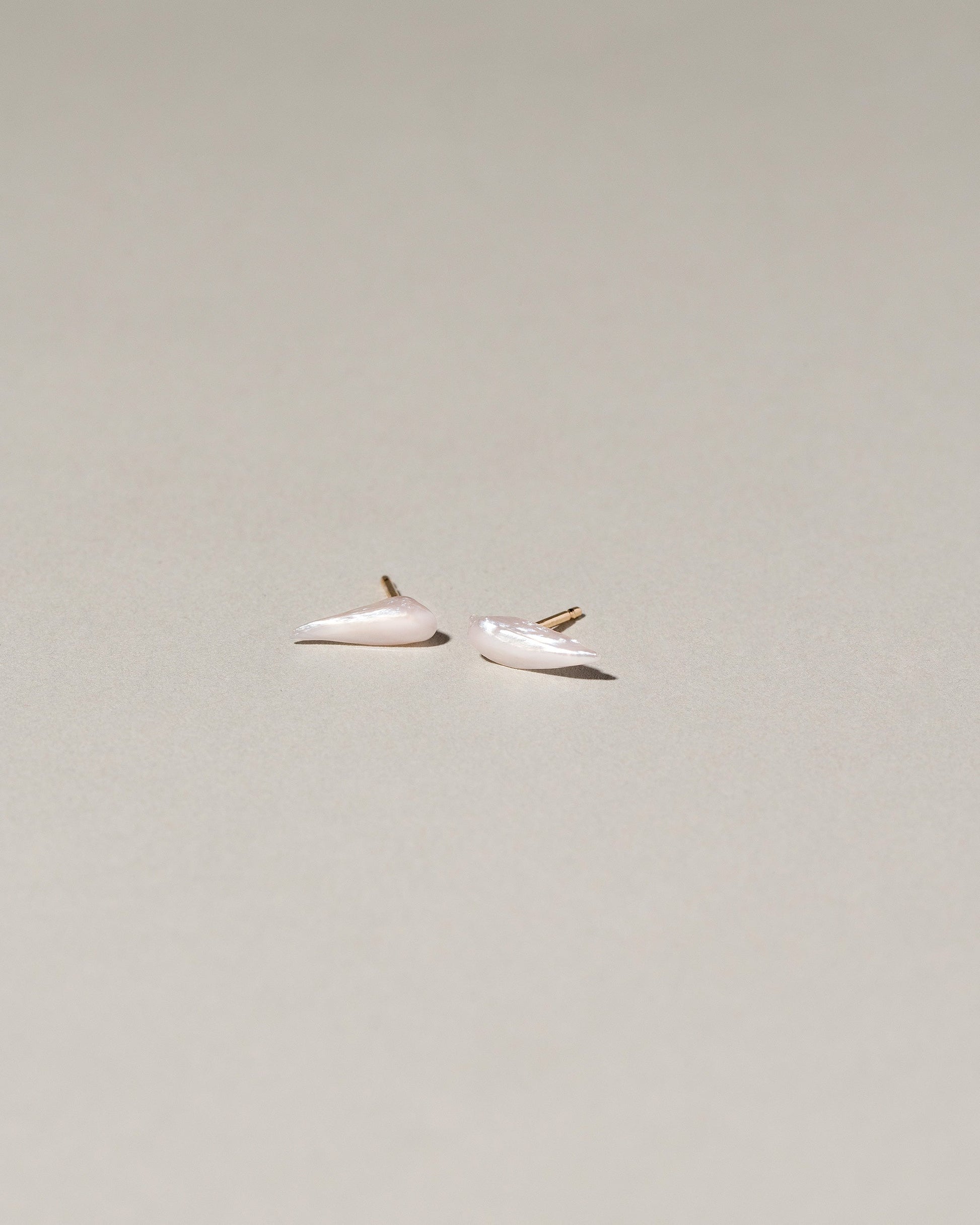 Wing Pearl Stud Earrings on light color background.