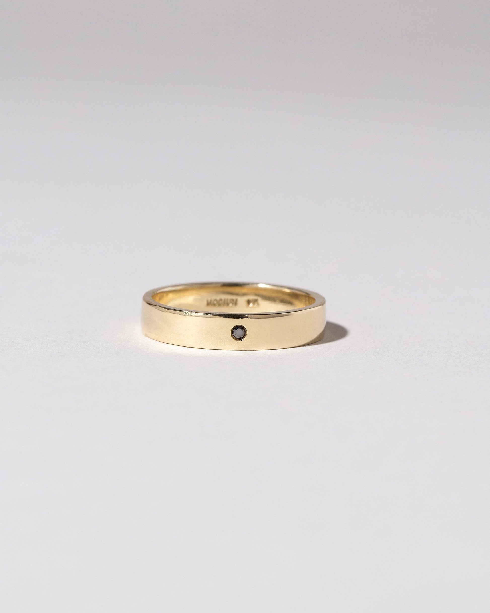 Closeup detail of the Gold 4mm Square Wire Band with Single Stone Black Diamond 1.6mm added on light color background.
