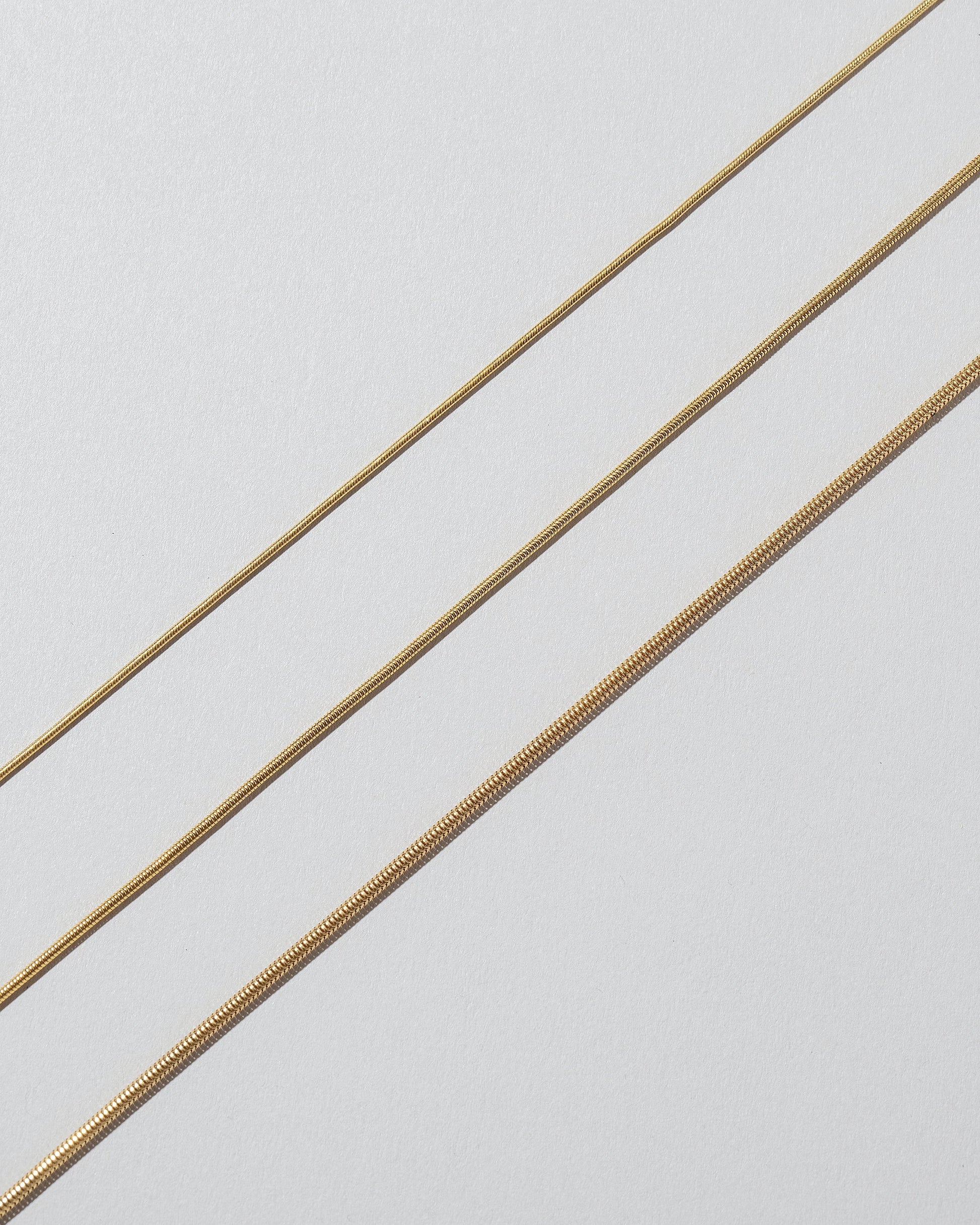 Closeup details of the 0.9mm Serpent Chain Necklace, 1.2mm Serpent Chain Necklace and 1.6mm Serpent Chain Necklace on light color background.