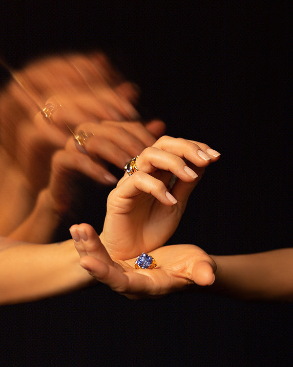 Styled long exposure image featuring the Alluim Ring in models hand on dark color background.