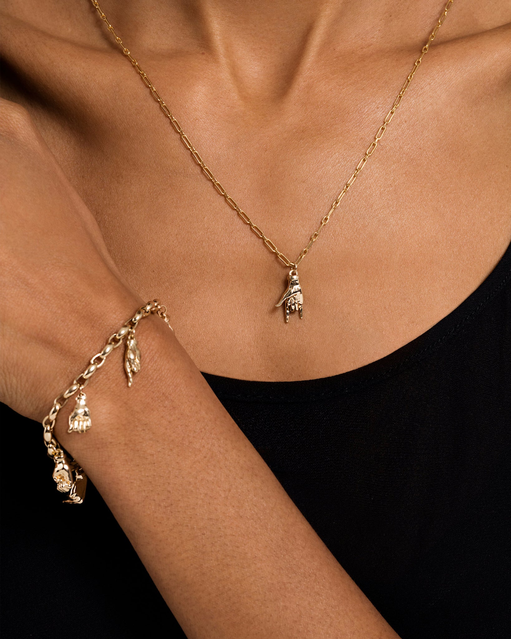 Model wearing a Sign Language Charm as a pendant on a chain and a charm bracelet with multiple Sign Language Charms