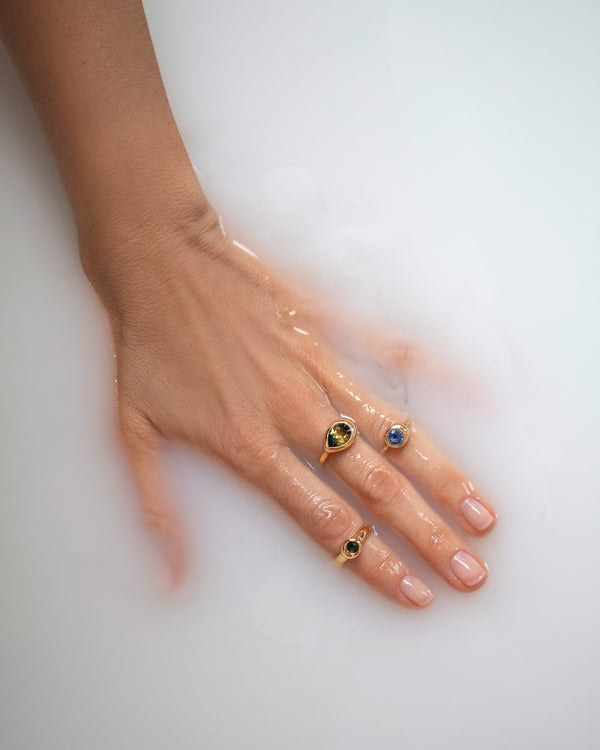 Photo of hand inmilky water wearing a stack of rings from the Level Collection.
