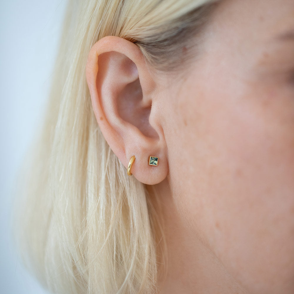 product_details::Petite Bicolor Green Sapphire Square Frame Stud Earring on model.