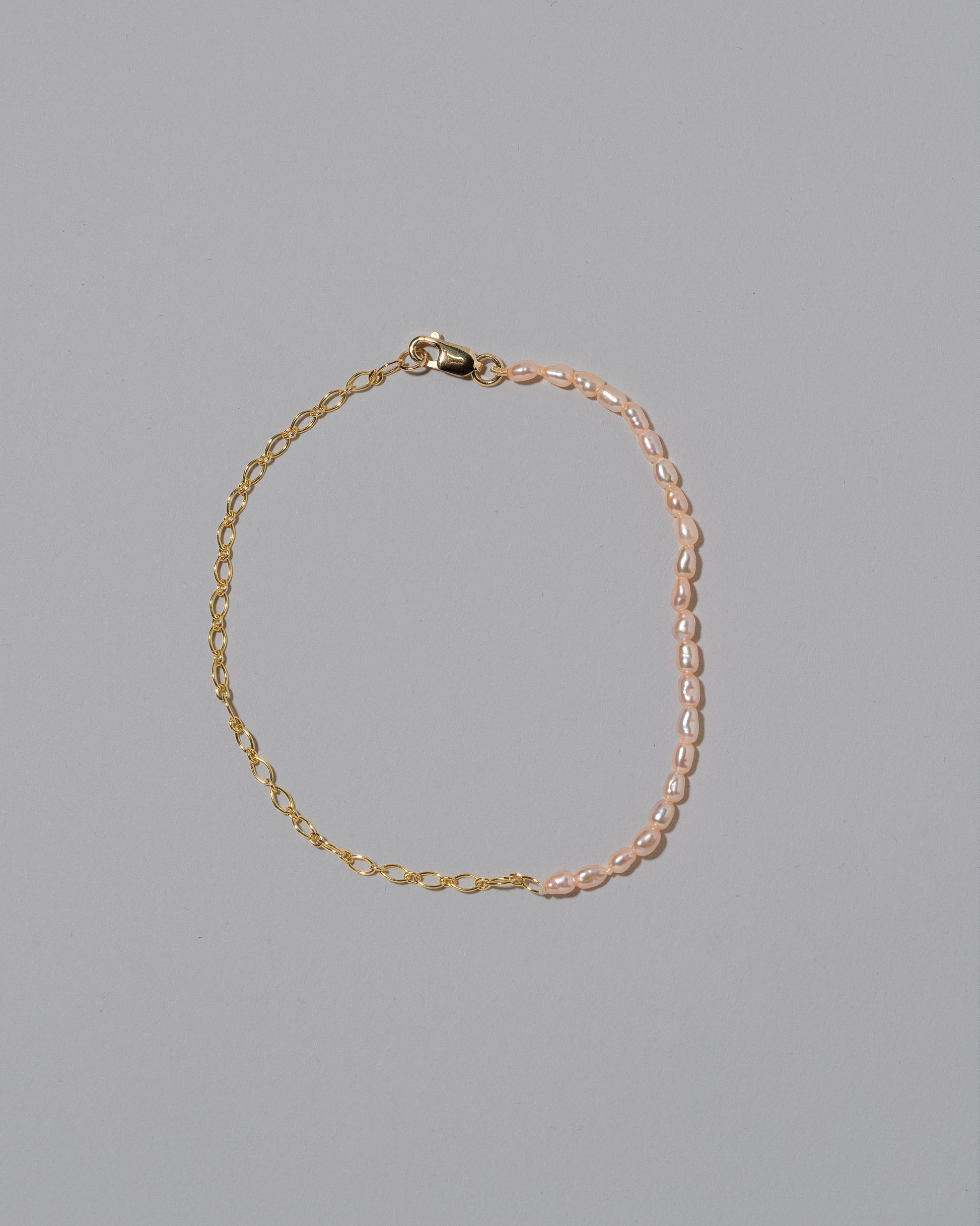 Half Oval Chain & Peony Seed Pearl Bracelet on light color background.