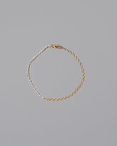 Half Oval Chain & White Seed Pearl Bracelet on light color background.