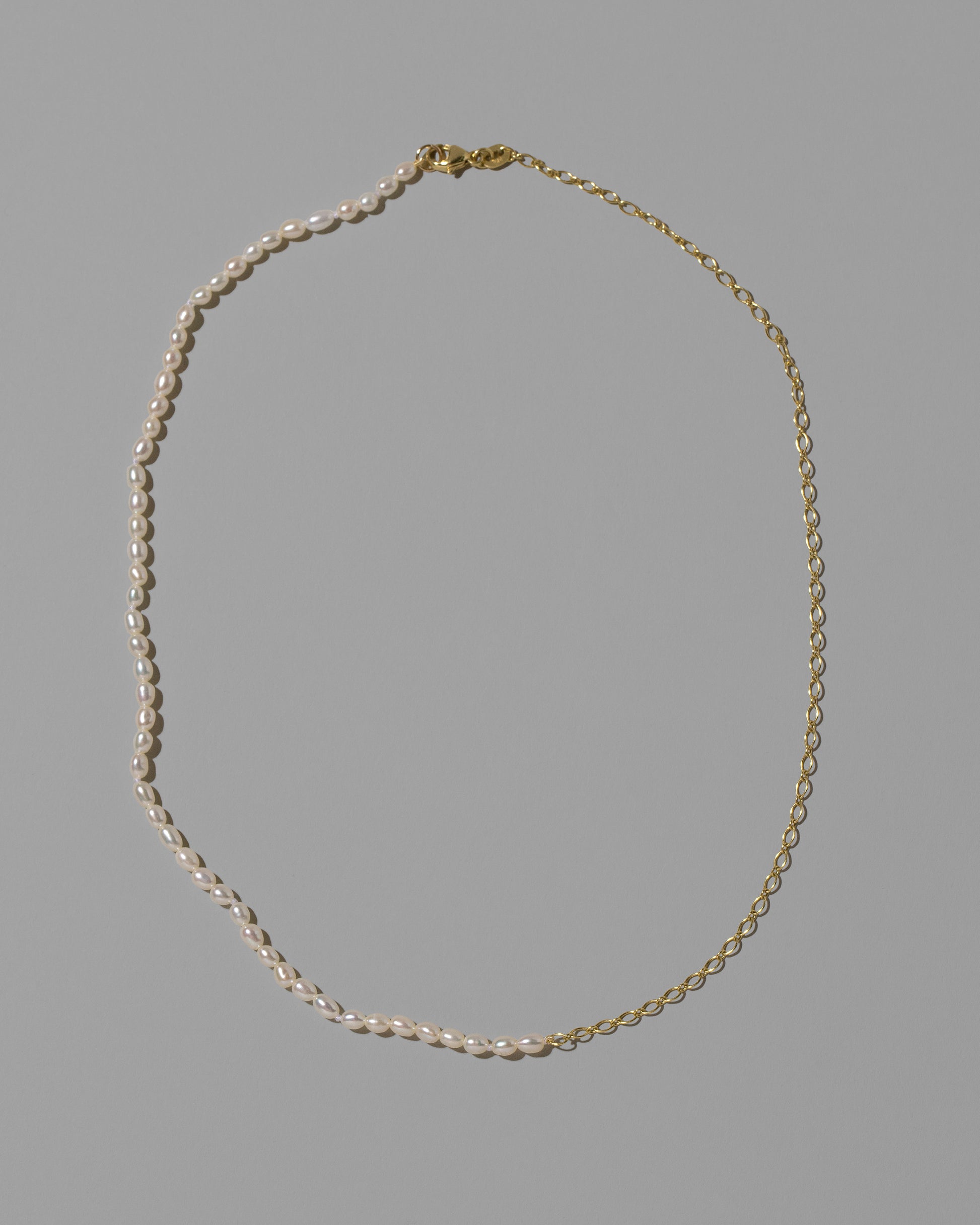 Half Oval Chain & White Seed Pearl Necklace on light color background.