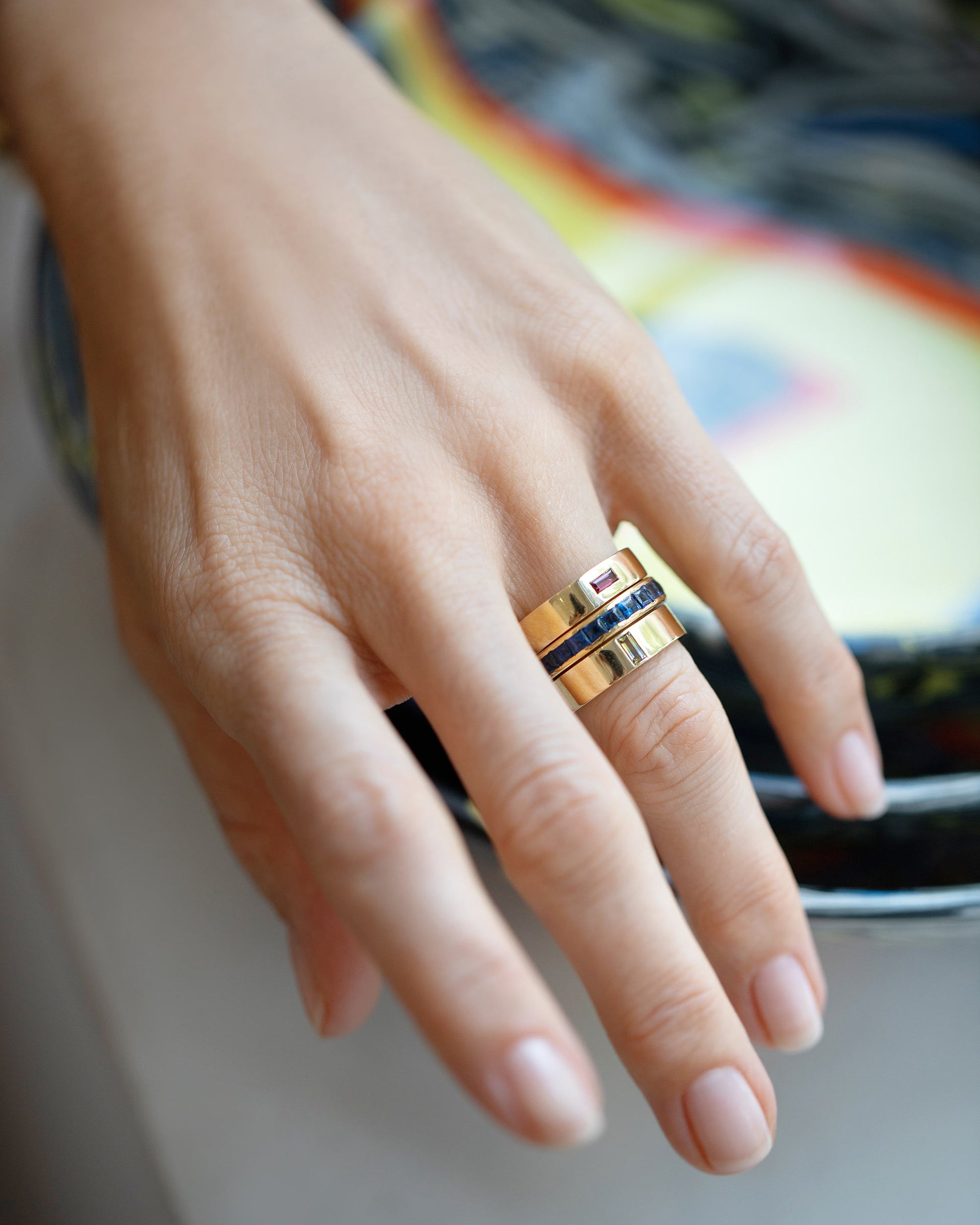 Styled image featuring the Gold Anthill Red Garnet East West 5mm Baguette-Set Piet Band, Gold Montana Bicolor Sapphire North South 5mm Baguette-Set Piet Band and the Vintage Cartier Sapphire Eternity Band.