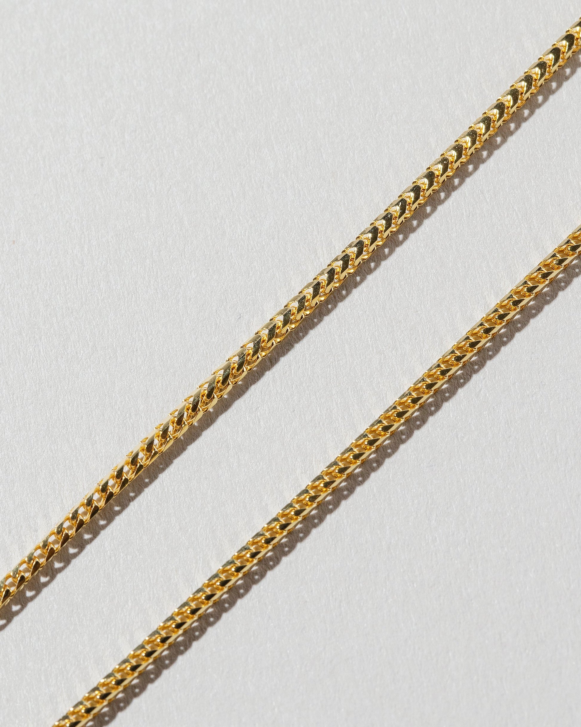 Closeup view of the Gold 18" 1.5mm Ritual Chain Necklace on light color background.