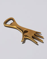 Closeup detail of the Carl Auböck Brass Hand Bottle Opener on light color background.