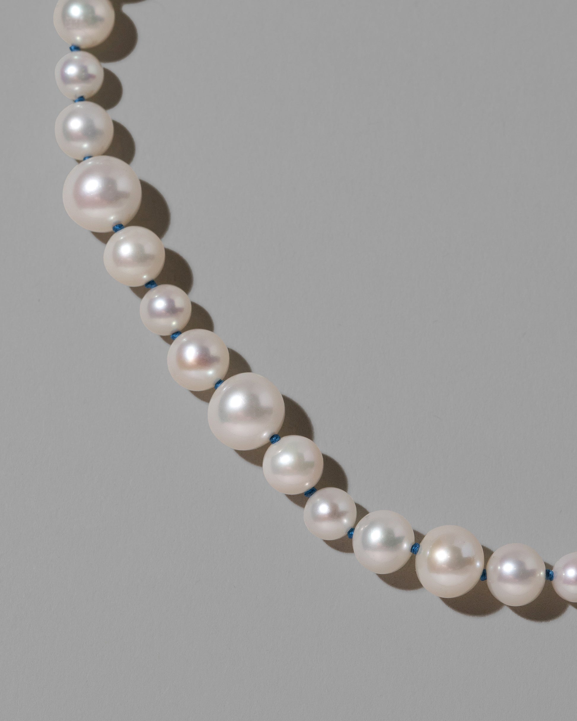 Closeup details of the Indigo Blue Thread Bubble Pearl Necklace on light color background.