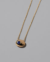 Closeup details of the Yellow Gold Bicolor Blue Sapphire Level Necklace on light color background.