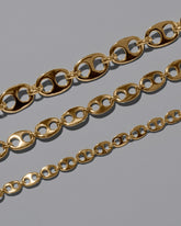 Closeup details of a group of CRZM One Gold Yuba Necklace Yuba Necklace and Yuba Medium Necklace and Yuba Mini Necklace on light color background.