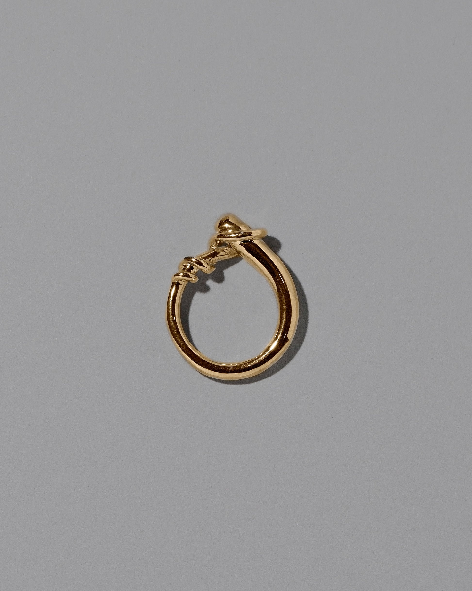 View from the side the of the CRZM 22k Gold Terrane Ring on light color background.