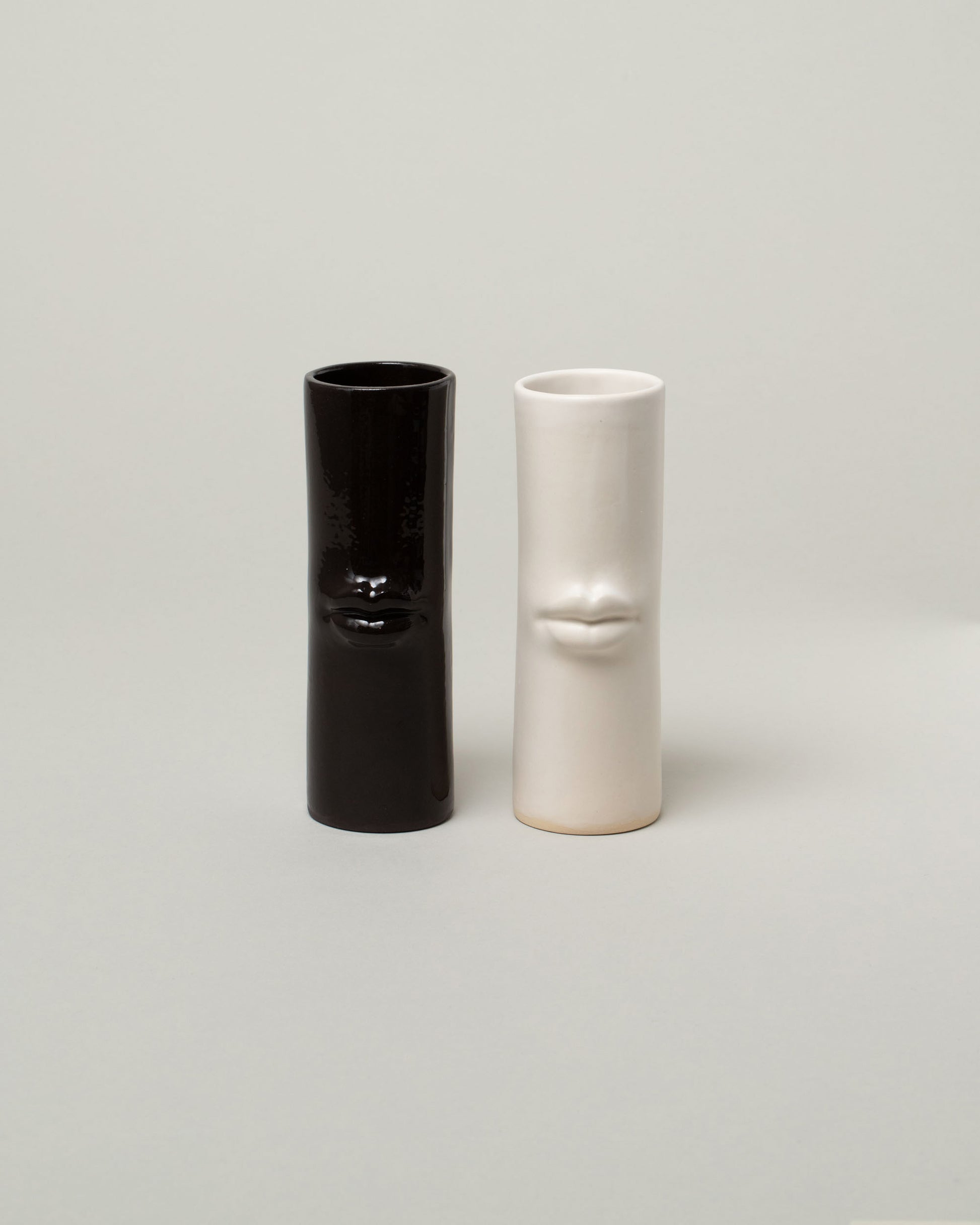 Group of Bonam Kim White and Black Lip Pillar Vases on light color background.